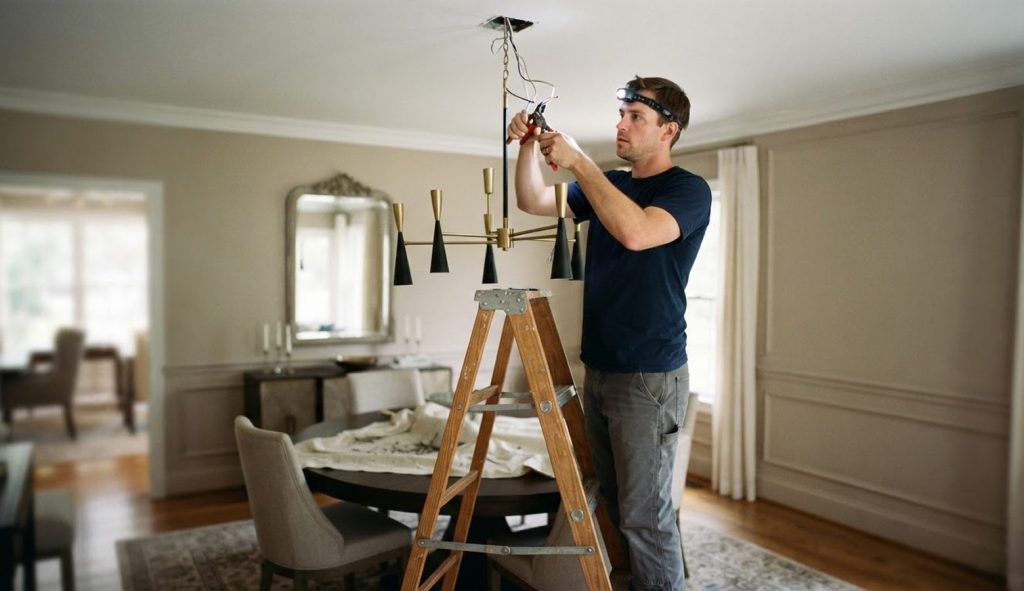 Electrician installing a chandelier in a dining room